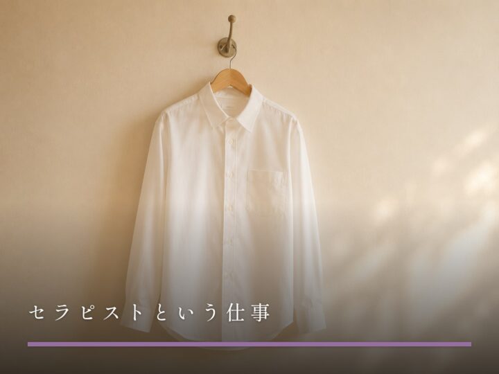 壁のフックに掛けられた木製ハンガーと、アイロンのかかった白いシャツ（セラピストという仕事）