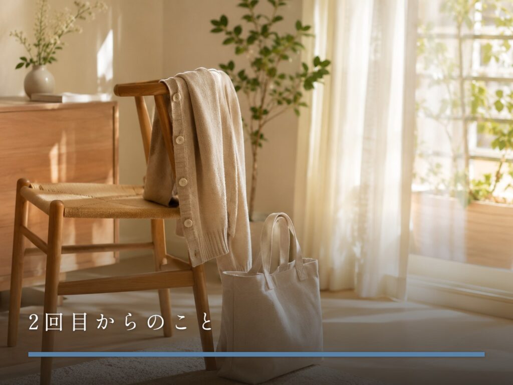 椅子の背にかけられたベージュのカーディガンと床に置かれた布製トートバッグ（2回目からのこと）