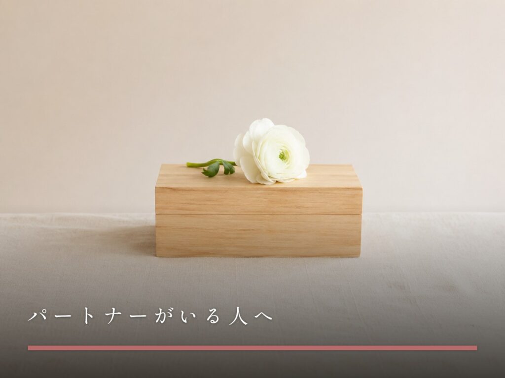 閉じたままの小さな木箱と、その上に置かれた一輪の生花（パートナーがいる人へ）