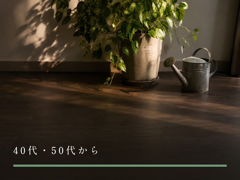 部屋の床に置かれた観葉植物の鉢と、使い込まれた金属のじょうろ（40代・50代から）