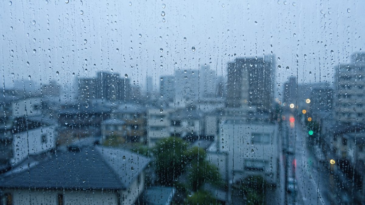 雨に濡れた窓ガラスと、その向こうのぼけた景色