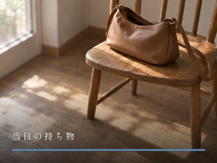木の椅子に置かれた、口を少し開けた革のショルダーバッグ（当日の持ち物）