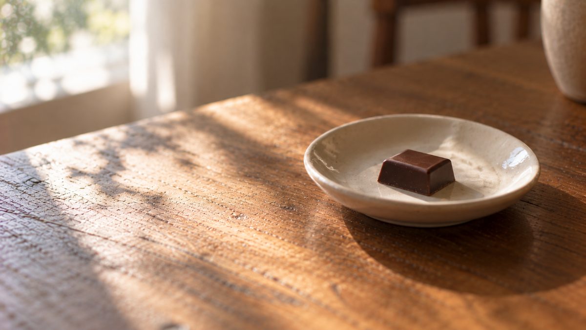 白い小皿に残された、包み紙のないひと粒のチョコレート
