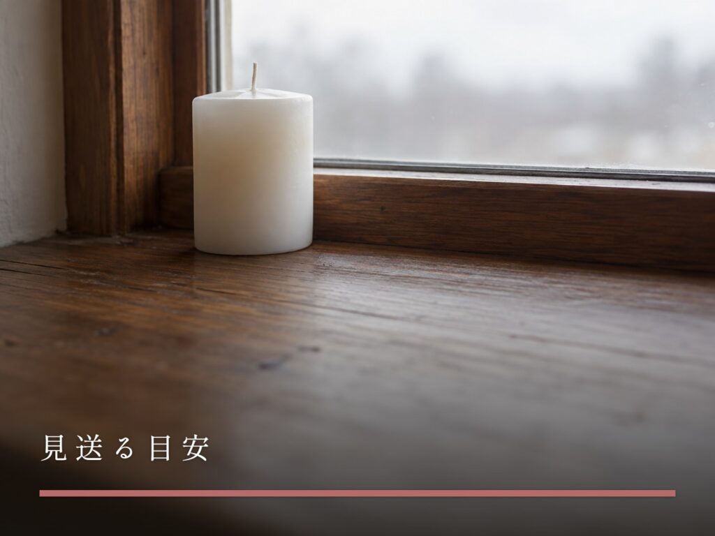 窓辺に置かれた、火のついていない白いキャンドル（見送る目安）