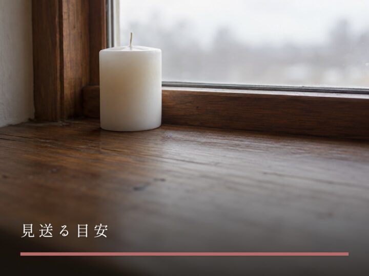 窓辺に置かれた、火のついていない白いキャンドル（見送る目安）